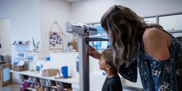 Caregiver weighing and measuring child