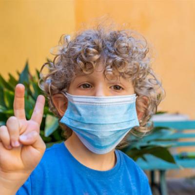 Boy with mask holding up fingers in peace sign