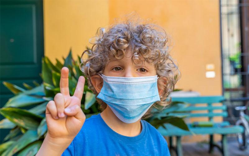 Boy with mask holding up fingers in peace sign