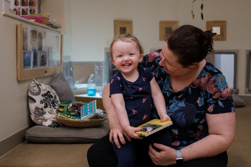 Child sitting with educator and smiling